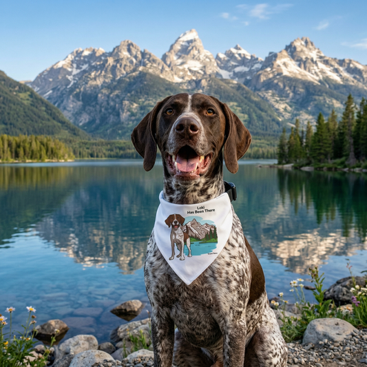 A German Shorthaired Pointer dog is wearing Bondarly's personalized dog national park clip-on bandana, sitting in front of a lake of the Grand Teton National Park. National Park Series.