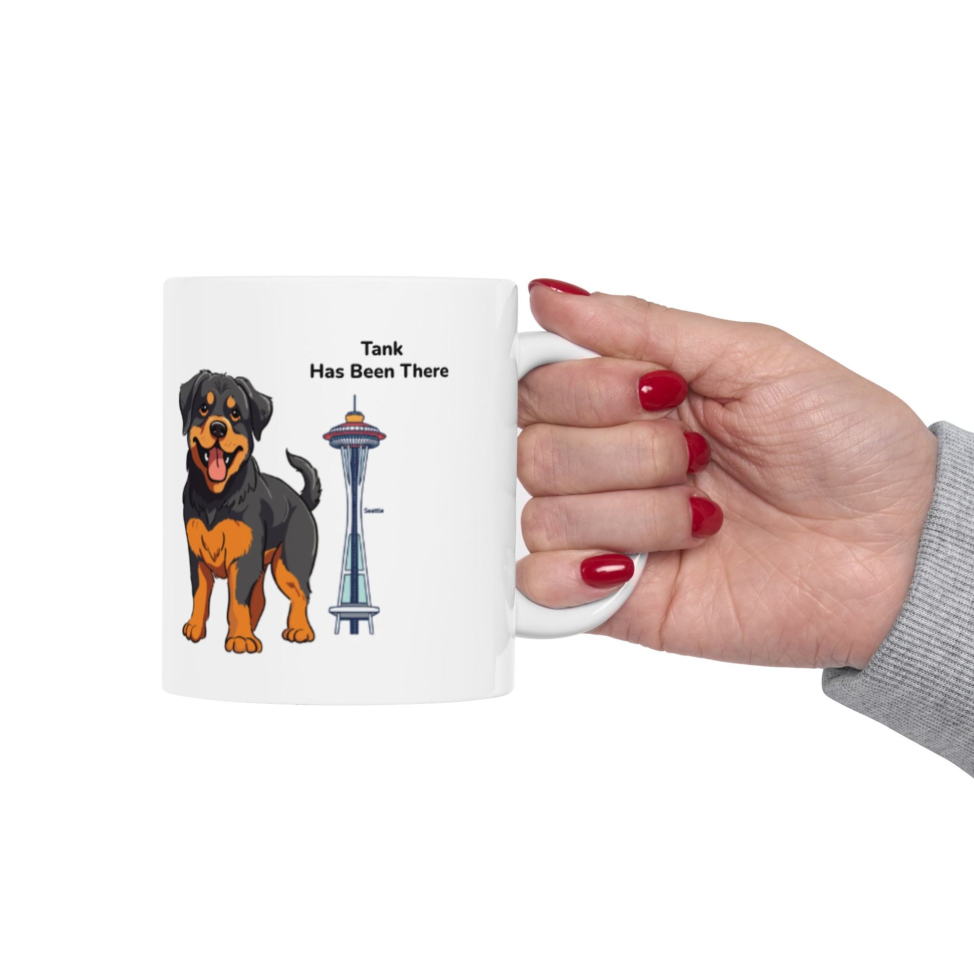 Hand holding a personalized mug, photographed from the right hand side with a dog illustration, dog name, "Has Been There" badge, and Seattle's Space Needle illustration. World Travel Series.
